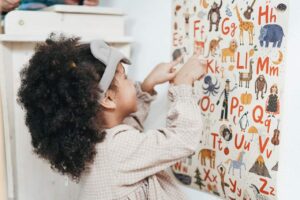 A little girl pointing at the alphabet.