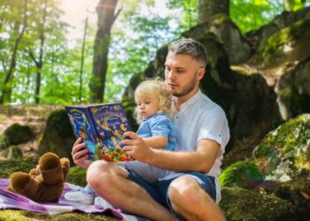 A man reading a book to her daughter