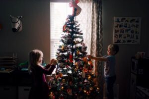 Two kids decorating a Christmas tree