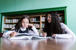 Girls in School Uniform Studying in the Library
