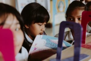 Little girl reading a book together with her friends